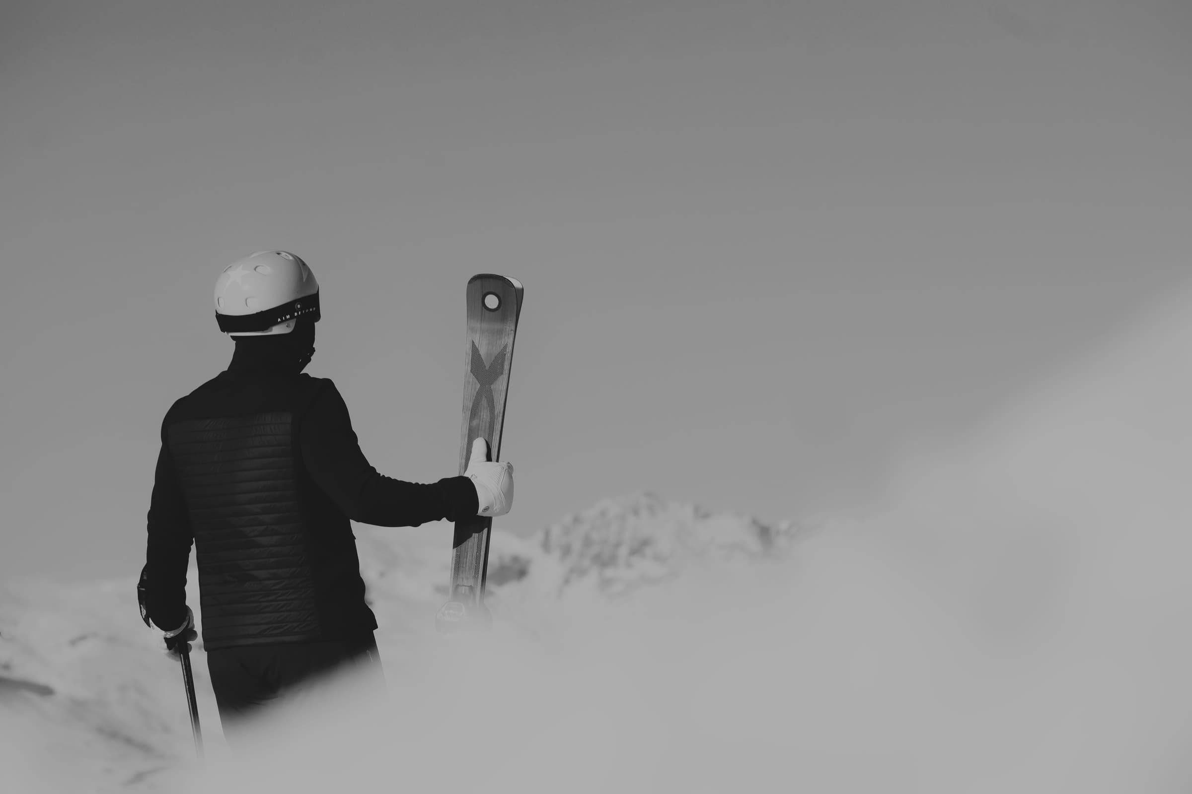 Skier seen from behind, skis in hand, Courchevel 1850, black and white