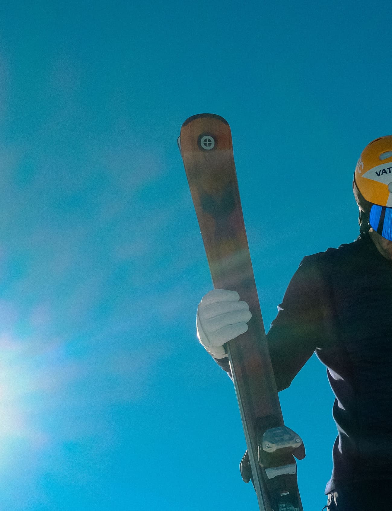 Ski instructor carrying his skis under a blue sky